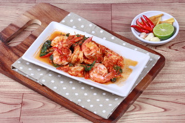 Fried spicy basil with shrimp and side dish as halve green lemon ,red chili and garlic are popular Thai food. 