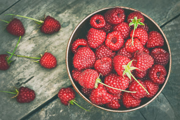 Fresh raspberries in wooden bowl on grey rustic wooden background. Top view