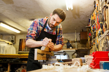 carpenter working with plane and wood at workshop