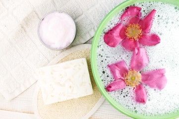 Obraz na płótnie Canvas Natural cleansing skincare spa treatment. Bowl with rose and foam, soap bar, exfoliator, moisturizer jar. 