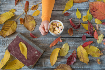 Female hand holding cup of coffee on wooden background. Autumn c