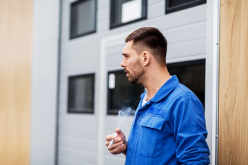 auto mechanic smoking cigarette at car workshop