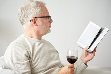 senior man drinking wine and reading book
