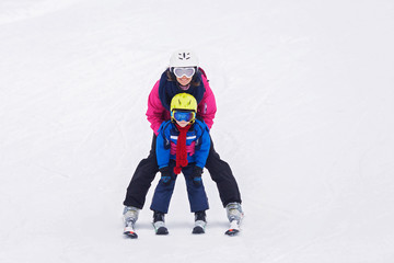 Sweet young boy and his mother, learning to ski on a mild ski sl