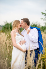Portrait kissing family in anticipation of the baby. Soft and romantic in nature photography
