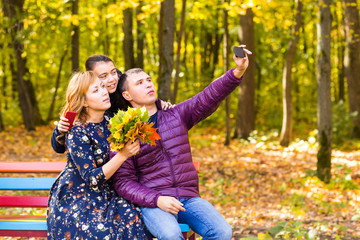 Fototapeta premium family, childhood, season, technology and people concept - happy family photographing in autumn park