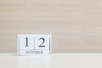 Closeup surface white wooden calendar with black 12 october word on blurred brown wood desk and...