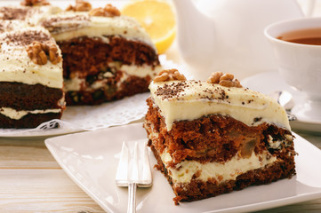 Piece of carrot cake with cheese cream on white background.