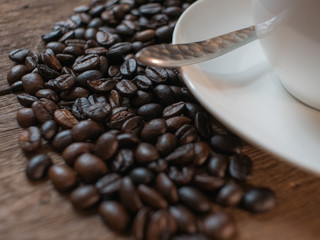 Coffee beans and coffee cup on wooden desk background.
