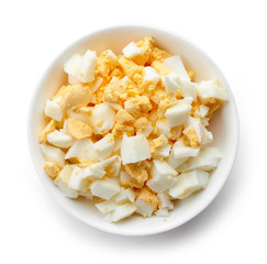 Bowl of chopped boiled egg, isolated on white, from above