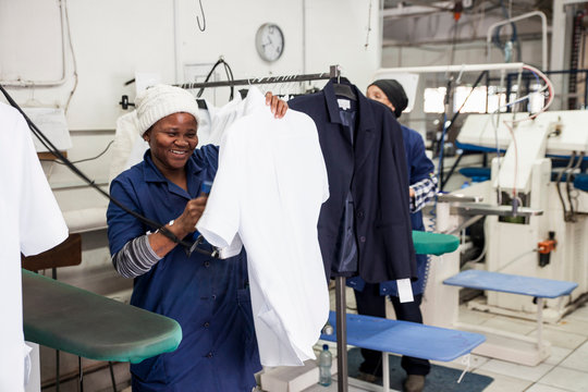 Worker ironing shirt in garment factory - Powered by Adobe