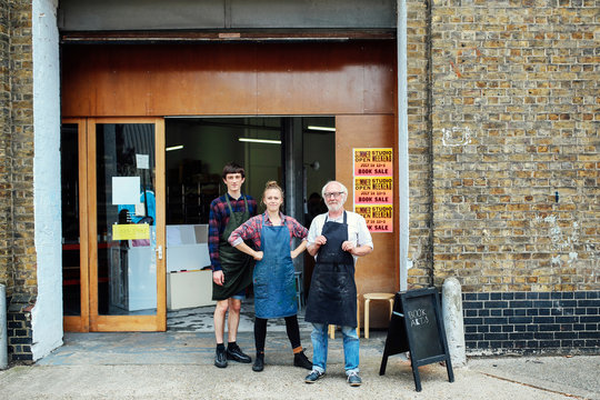 Family portrait of senior craftsman with daughter and son outside print workshop