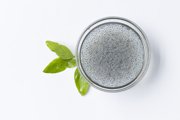 Sweet basil seed in glass bowl and fresh leaf on white background