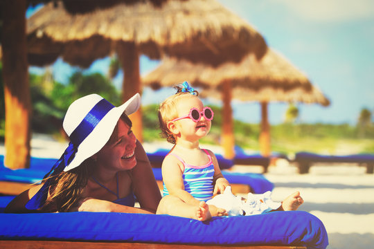 mother and cute little daughter having fun on summer beach