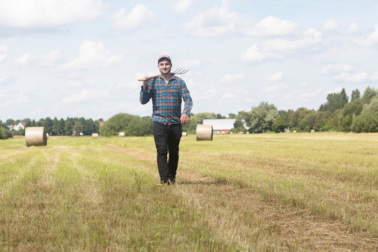 Farmer in field carrying spade on shoulder