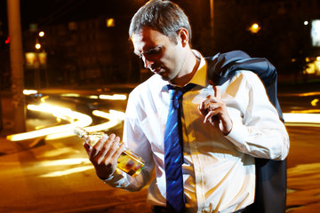 Fototapeta na wymiar Portrait of a businessman with a bottle of whisky at night