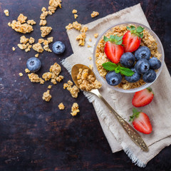 Homemade muesli granola in glass with berries on rusty table