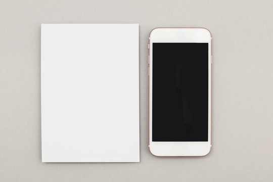 Blank white postcard flyer alongside a smartphone with a blank screen