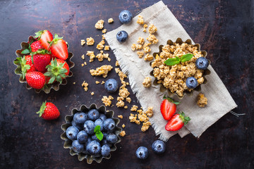 Obraz na płótnie Canvas Homemade muesli granola in bowl with berries on rusty table