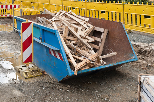 Ein blauer Container mit Holzabfall auf einer Baustelle