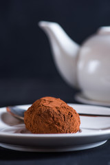 Chocolate truffle on white platter over dark background