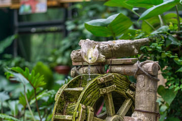 Water flow from bamboo conduit and powering the waterwheel in the tropical garden