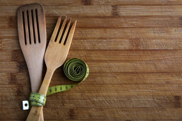 Cubiertos de madera con una cinta metrica (concepto de dieta y comida sana)