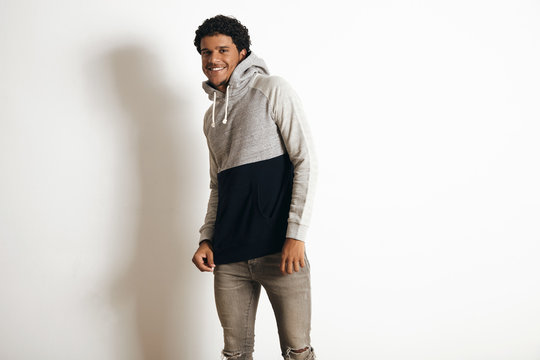 Happy smiling attractive latino guy wears blank grey black sweater with hood and distressed jeans, isolated on white