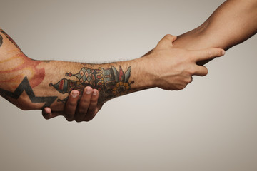 Close up of a forearm Roman, Civil war handshake of two young men, one with tattoos, on white...