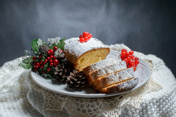 Traditional fruitcake for Christmas decorated with powdered sugar and fresh berry