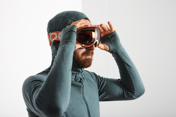 Portrait of bearded male athlete in baselayer thermal suite wears snowboarding googles