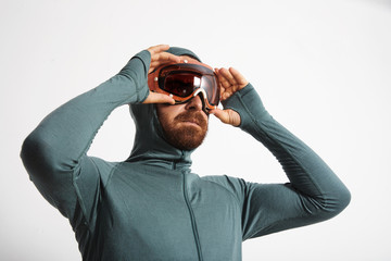 Bearded male athlete in baselayer thermal suite wears snowboarding googles