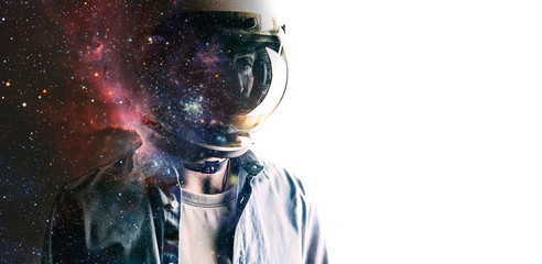Casually dressed sad looking man in a large helmet with bright stars and galaxies projected on the shield and behind his back with white background in front of him. Double exposure
