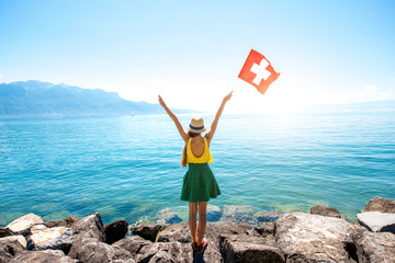 Young female traveler with swiss flag enjoying great view on Geneva lake in Switzerland