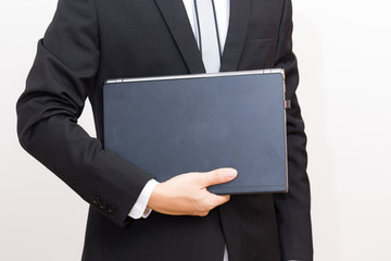 Handsome young man wearing black suit hold laptop computer