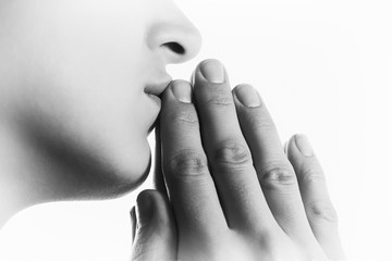 Black and white image of  a  woman  during a prayer on white background. Her hands touchs  a lips. © svetazi
