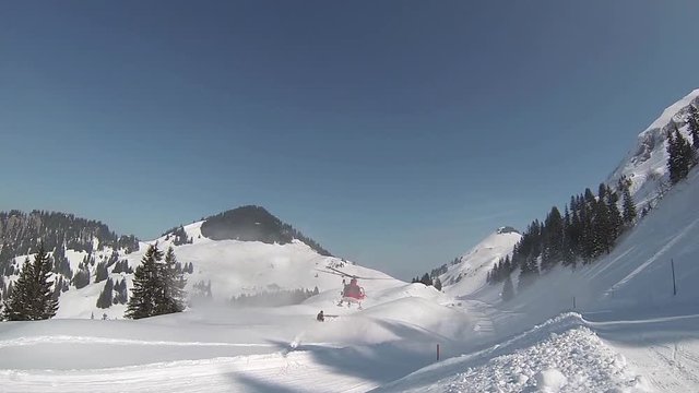 Landing rescue helicopter in a skiing region raises snow with the rotor blades while landing