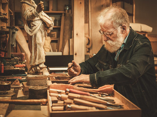 Senior restorer working with antique decor element in his workshop