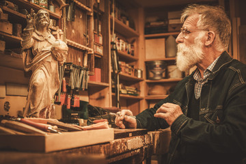 Senior restorer working with antique decor element in his workshop