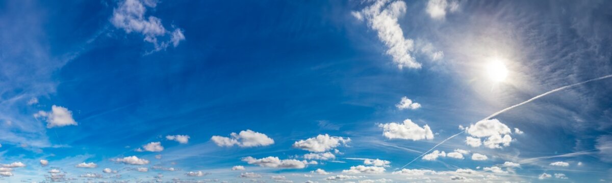 Blue sunny sky with fluffy clouds. Huge panorama