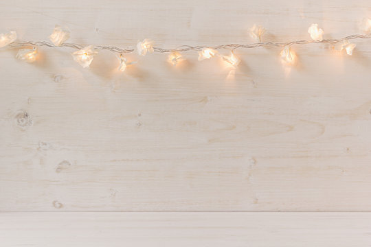 Christmas lights burning  on a white wooden background. Xmas background.