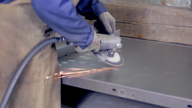 Worker using industrial grinder operating with metal at a metal processing plant. HD.