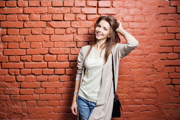 Young beautiful happy woman in casual cloths against brick wall