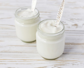 Homemade yogurt in glass jar on wooden table.