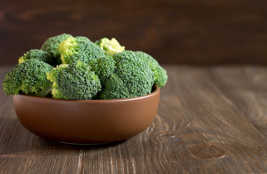 Fresh broccoli in a brown plate on the wooden rustic table.