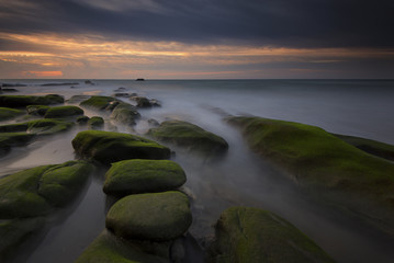 Beautiful sunset decorated with waves and mosses stone