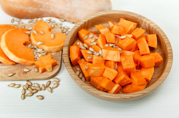 Cut Pieces of Pumpkin with seeds in Wooden Plate on the Wooden Board.Harvest,Fresh Vegetable, Ingredient.White Food Background.