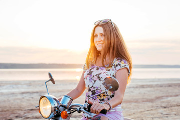 Young pretty woman with tattoo riding a bike and enjoing the sunset at the seaside