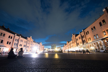 夜の赤いレンガの倉庫と女性たちの影