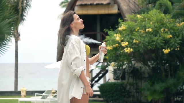 Young woman in shirt applying deodorant on body in garden, super slow motion 240fps
